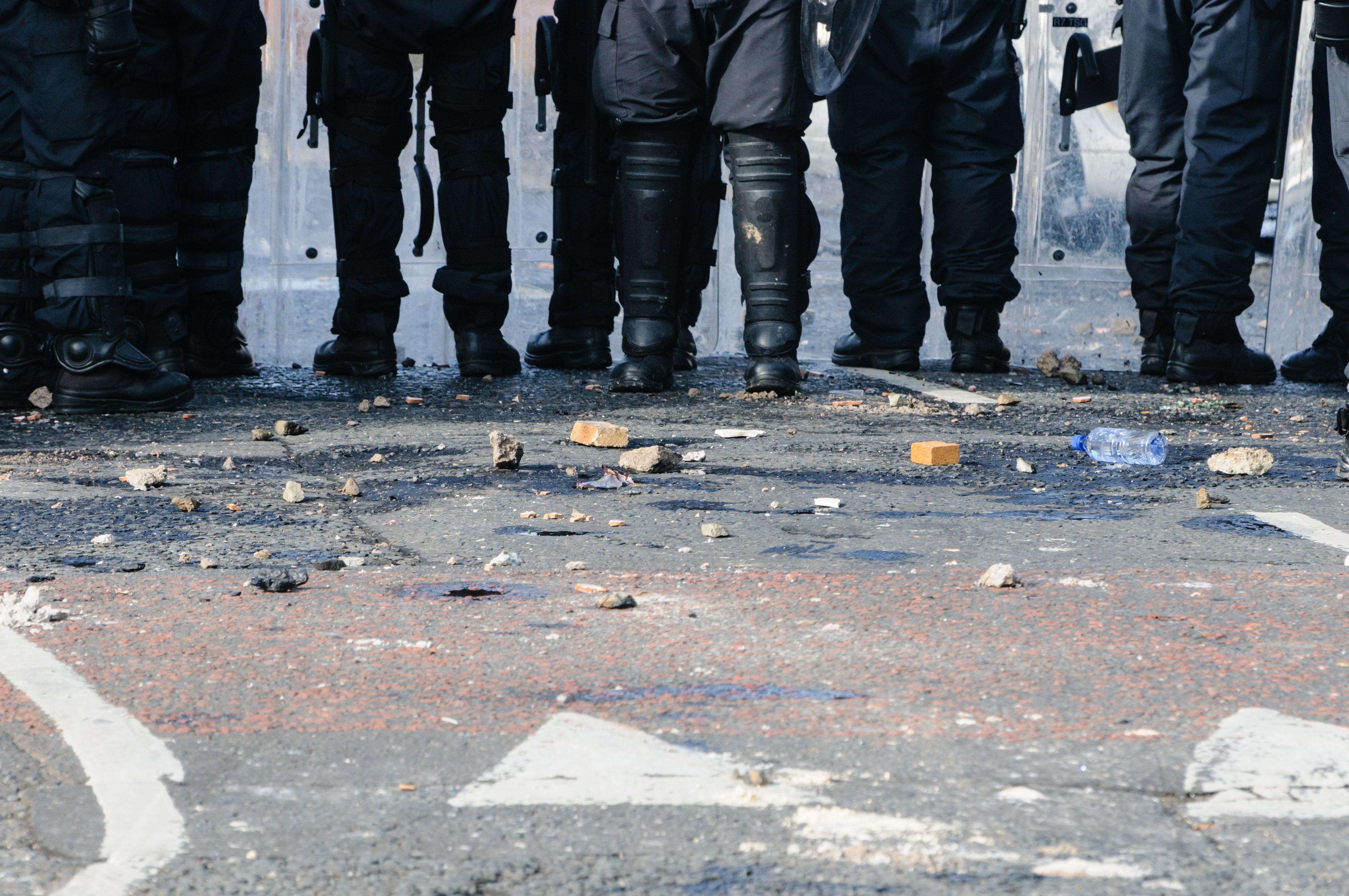 Police officers at a riot. Shows their lower half with debris on the street. 
