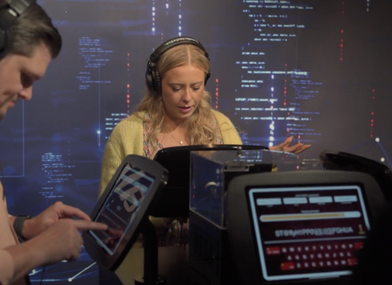 Four people wearing headphones interact with digital displays in front of an AtkinsRéalis-branded backdrop.