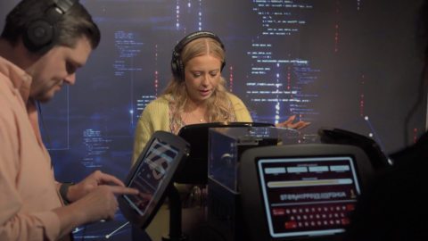 Four people wearing headphones interact with digital displays in front of an AtkinsRéalis-branded backdrop.