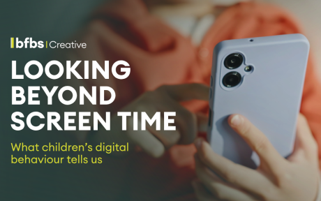 BFBS Creative banner featuring the headline "Looking Beyond Screen Time" and the subtitle "What children's digital behaviour tells us". In the background, a child wearing an orange top holds and uses a smartphone while seated indoors.