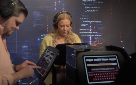 Four people wearing headphones interact with digital displays in front of an AtkinsRéalis-branded backdrop.